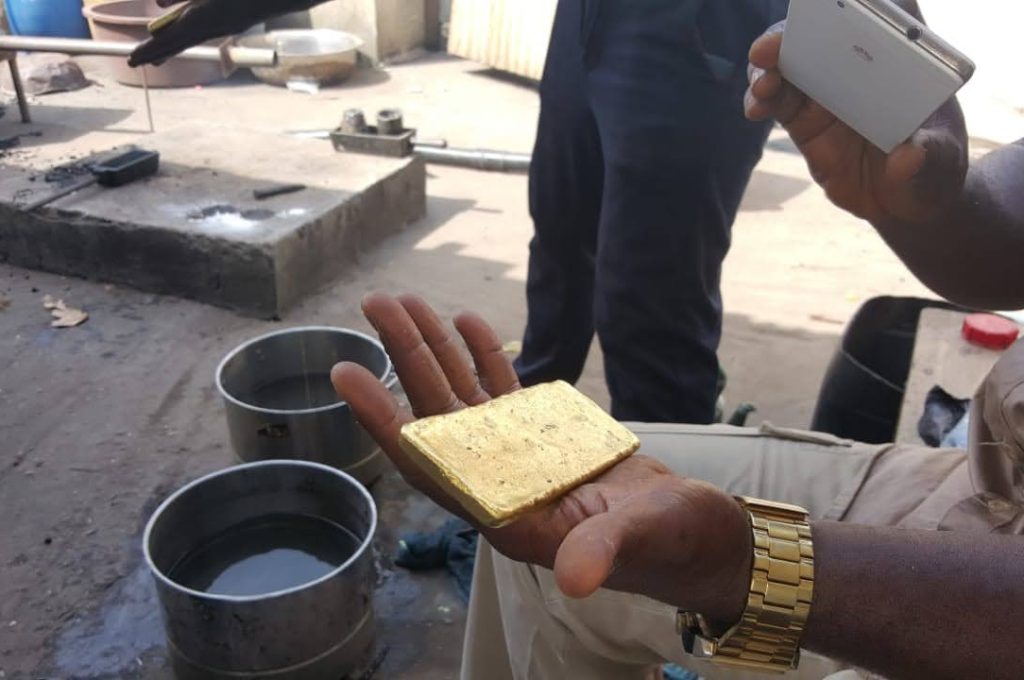 A man grips a gold bar, highlighting processed gold sourced from a new mining operation in Liberia