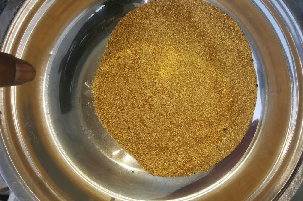 A hand holds a bowl of gold dust, symbolizing gold discovered at a new mining site in Liberia.